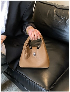 Detail of dark brown pebble leather bucket bag with silver metal swivel lock and handle