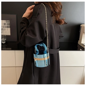 Metallic blue cylinder evening bag with gold chain strap shown in a chic fashion setting