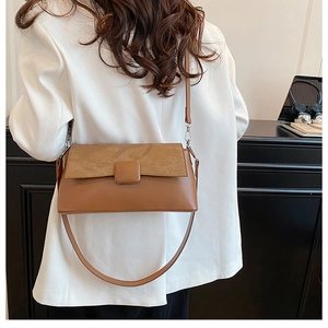 Braune Unterachseltasche mit Textur-Paneel an Model in weißem Blazer präsentiert