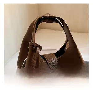 Detail of dark brown lychee leather bucket bag showing the handle and metal lock buckle