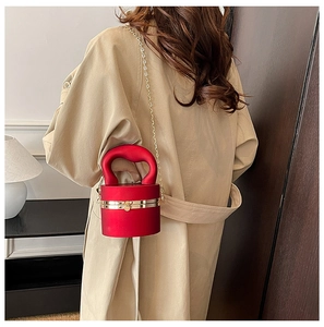 Detail of red cylindrical evening bag with circular handle and gold chain strap
