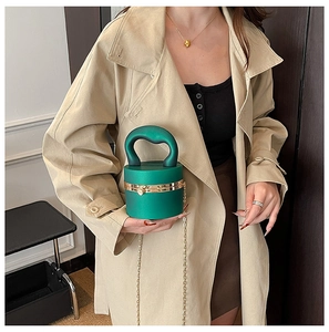 Detail of dark green cylindrical handbag with gold hardware and top handle strap