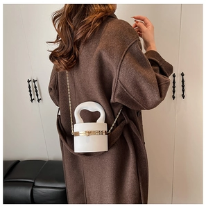 Rear view of model with white cylindrical acrylic bag featuring gold chain and curved handle