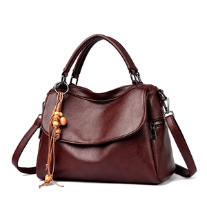 Sac à main vintage en cuir bordeaux avec pompon et bandoulière réglable pratique