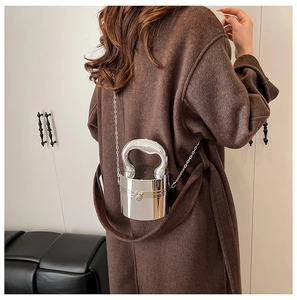 Detail of silver bucket bag with U-shaped handle and metal chain on a wool coat