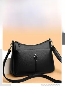 Detail of black pebbled leather crossbody bag featuring a silver crest logo and front pocket