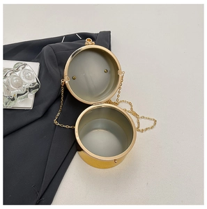 Macro view of golden round metal clutch with spherical clasp and long chain strap