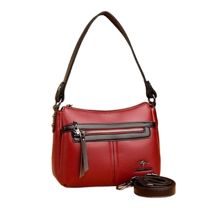 Red pebbled leather crossbody bag with kangaroo logo and adjustable strap on white background