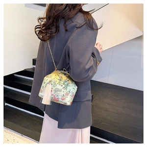 Green silk frame bag with oriental lady print and pink tassel shown on model in stairwell