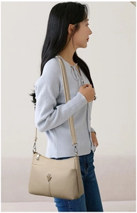 Detail of minimalist beige crossbody bag featuring lychee grain texture and metal hardware
