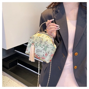 Detail of green silk clutch bag with traditional pattern, metal handle and tassel