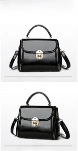 Detail of black glossy leather handbag featuring golden lock and decorative side zippers