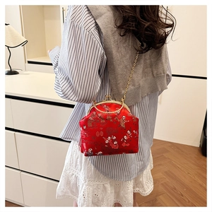 Detailed view of a red Chinese jacquard clutch bag with golden chain on a model