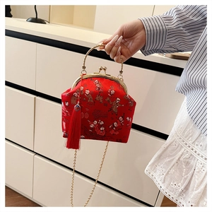 Detail of red brocade evening bag with golden handle, chain strap and silk tassel