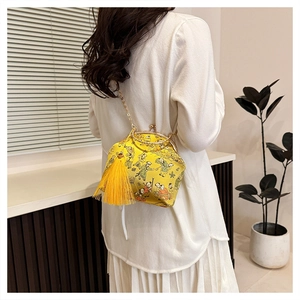 Detail of yellow silk evening bag with traditional print and decorative tassel charm