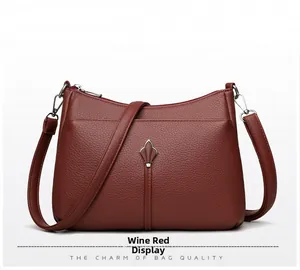 Detail of wine red crossbody bag showing lychee grain leather texture and metal buckle
