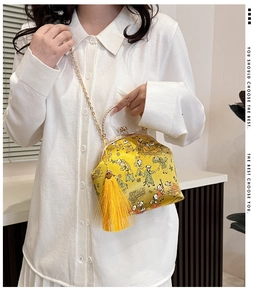 Macro detail of silk yellow evening bag with traditional print and metallic clasp