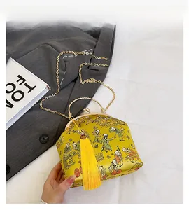 Detail of yellow satin evening bag with traditional illustration and silk tassel
