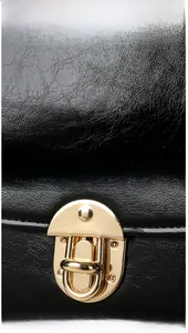 Close-up of black lychee grain leather handbag featuring a vintage gold semi-circle lock