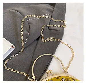 Detail of vintage evening bag showing bronze metal chain strap and floral metal handle