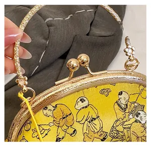 Close-up of vintage yellow brocade clutch with ornate gold metal frame and embroidery