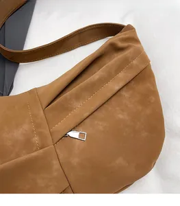 Close-up detail of the brown faux suede shoulder bag with soft pleated texture and metal zipper