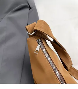 Close-up of a silver metal zipper and durable brown synthetic leather strap detail