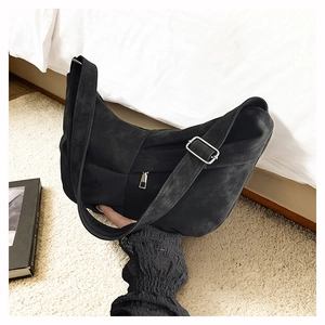 Close-up of black suede hobo bag with adjustable wide strap and silver metal buckle