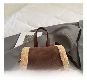 Close-up of the dark brown leather handle on a brown suede backpack with faux fur trim