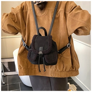 Detail view of mini black suede backpack featuring faux shearling trim on model