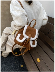 Detailed view of brown corduroy backpack with white faux shearling trim and metal buckles