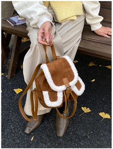 Brown suede backpack with white faux fur trim shown on a model in an autumn setting