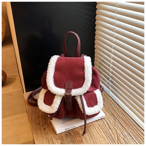 Close-up of burgundy suede mini backpack with white sherpa fleece trim and buckle detail