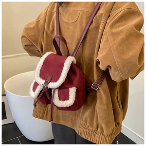 Detail of burgundy suede backpack with faux fur trim worn by a model in a retro style