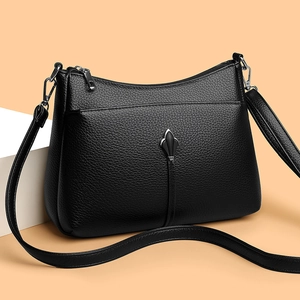Minimalist black pebble leather crossbody bag with silver hardware on a neutral background