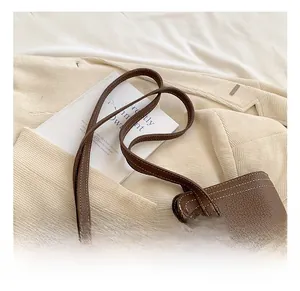 Detailed shot of brown litchi leather tote bag with white contrast stitching details
