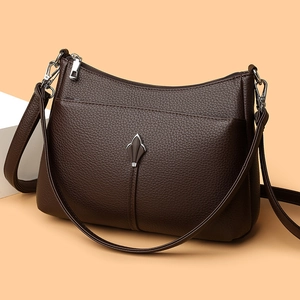 Minimalist dark brown lychee leather shoulder bag with silver emblem on warm backdrop
