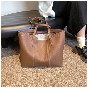 Detailed view of brown lychee leather tote bag with elegant white contrast stitching