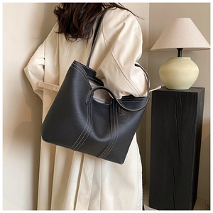 Detail of black pebbled leather tote bag with white contrast stitching and shoulder strap
