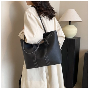 Detail of black tote bag with white contrast stitching and premium pebbled texture