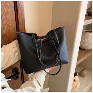 Detail of black leather tote bag with elegant white contrast stitching and grainy texture