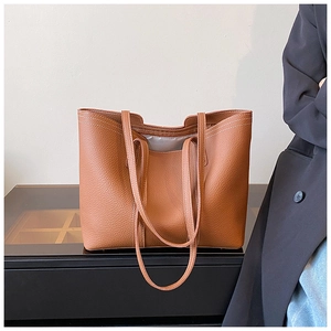 Detailed view of the brown lychee grain leather tote bag with fine stitching on a sleek surface