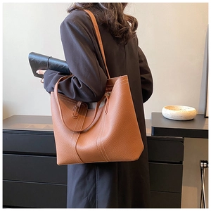Detail of caramel brown leather tote with white contrast stitching and long strap