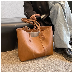 Detail of caramel brown tote bag featuring contrast stitching and soft pebble leather texture