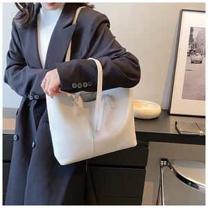 Close-up of white lychee leather tote bag worn with a professional black suit blazer