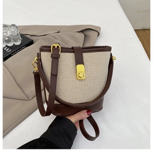Fashionable beige canvas bucket bag with brown leather trim and metal twist lock detail