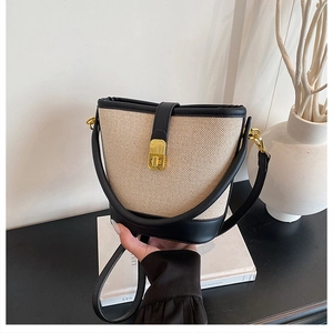 Detail view of the golden metal turn-lock and beige woven texture on the bucket bag