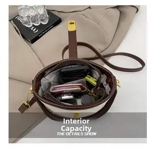 Internal capacity of beige canvas and brown leather crossbody bag with daily essentials