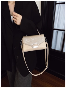 Model wearing beige flap crossbody bag with silver textured buckle for stylish commute