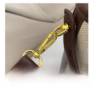 Macro shot of gold metal hooks and brown leather straps on a beige canvas bag